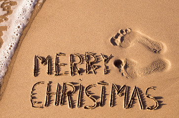 text merry christmas in the sand of a beach