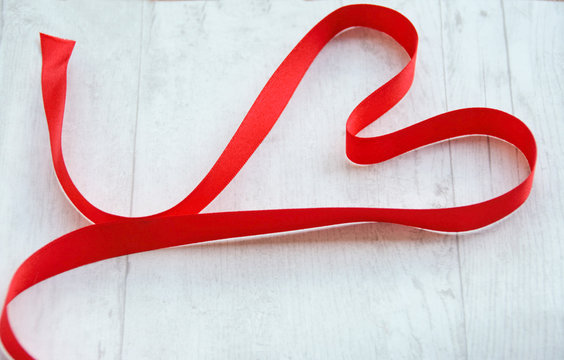 Romantic background ;  a ribbon in shape of heart on a white wooden background
