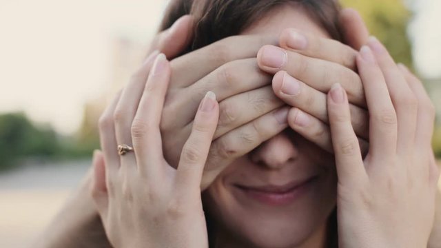 man covering the eyes of surprised girlfriend