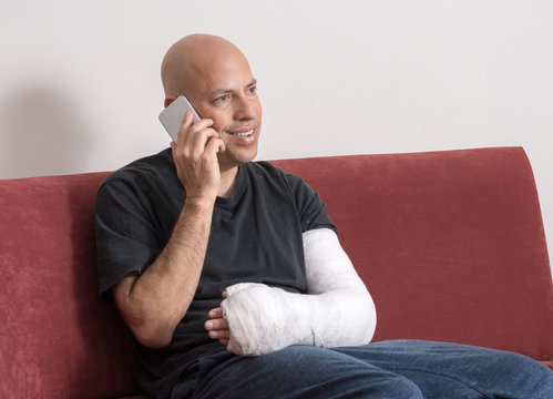 Young man with an arm cast talking on his phone