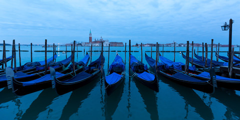 Fototapeta na wymiar View of Gondolas tied up at the side of the grand canal waiting on tourists. Showing view over the Grand Canal in Venice.