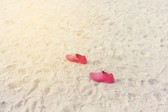 Red plastic shoes on the beach
