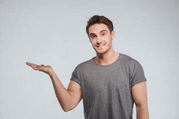 Portrait of happy cheerful young man holding copyspace on palm