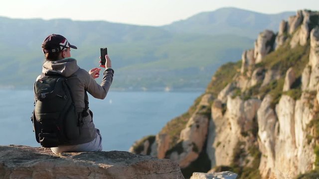 Young woman taking a self-portrait with her smartphone in the mountains