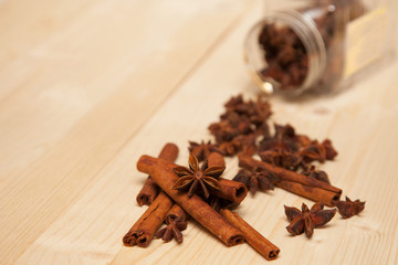 seasoning cinnamon (Cinnamomum) and anise (Anisium vulgare Gaerto) lies on a light wood surface, spilled from a jar,  close-up, background, healthy lifestyle