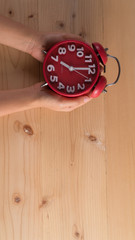 Red alarm clock in hand