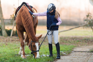 Young girl preparing horse for ride