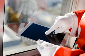 Santa Claus working at desk and using apps on a touch screen tablet