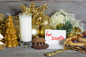 Milk and cookies for Santa Claus around gold decorations and Christmas toys 