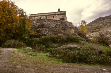 Fototapeta na wymiar Perched high in the mountains monastery for old stone wall in the autumn overcast day