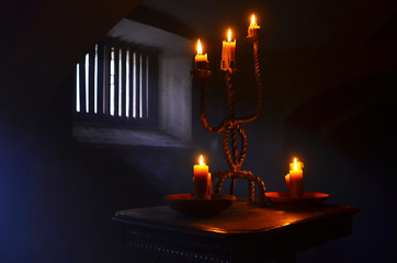 Antique candle burning in a dark room. Christmas Eve, divination, yuletide. Christmas backgrounds. holiday rituals, religion, spirituality, zen. space for text, close-up, copy space.