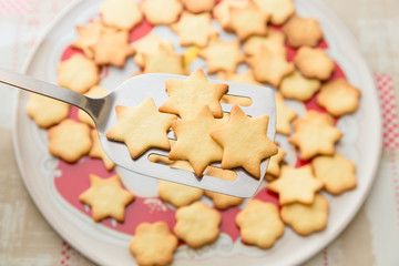 Biscotti artigianali a forma di stella appena sfornati su paletta di acciaio