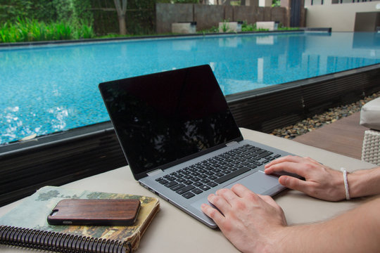 Blogger working by the pool and connecting on wifi to make money online using laptop computer.