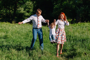 Obraz premium Cheerful parents walking in the park with his son