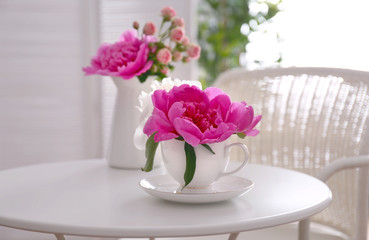 Flower bouquet of peonies in cup on table