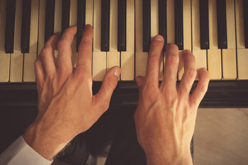 Man hands playing piano, close up