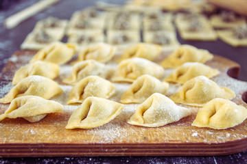 Freshly prepared Italian tortellini on wooden board
