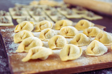 Freshly prepared Italian tortellini on wooden board