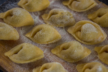 Homemade tortellini with mushrooms on black background close up