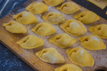 Homemade tortellini with mushrooms on black background close up