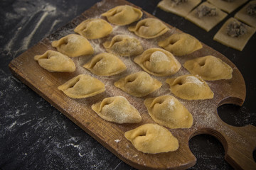 Homemade tortellini with mushrooms on black background