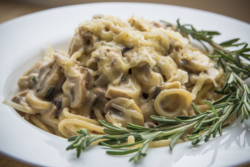 Pasta with creamy sauce, mushrooms and rosemary close up