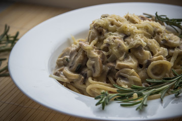 Pasta with creamy sauce, mushrooms and rosemary close up