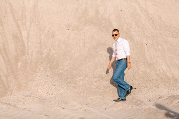 stylish man in sunglasses with a bristle on a background of sand