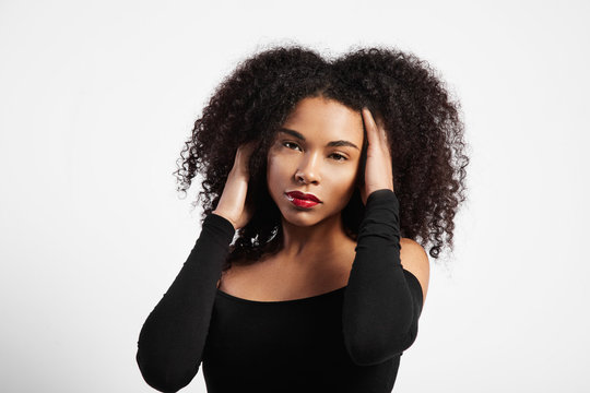black woman with ideal skin touching her black curly hair