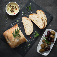 Italian ciabatta bread  on black slate with herbs and olives.