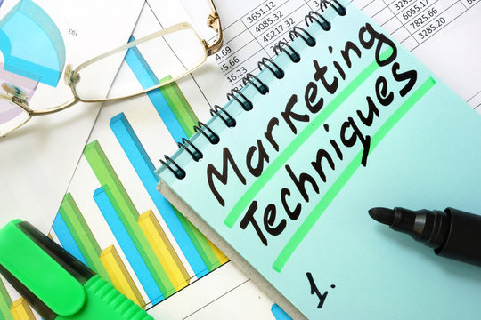 Notepad with sign marketing techniques on a table.