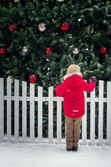 Childlooking at Christmas tree at snowfall