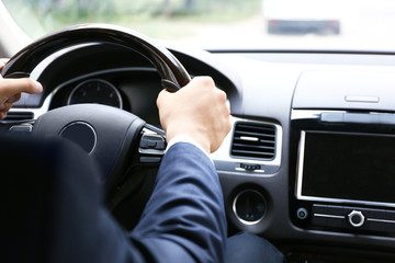 Fototapeta na wymiar Male hands on steering wheel, closeup