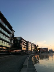 Moderne Architektur mit spiegelndem Glas im Licht der aufgehenden Sonne am Kreativkai an der...