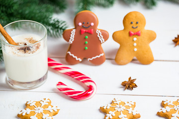 Christmas Gingerbread men with glass milk and festive branches fir. Homemade delicious gingerbread cookies on the wooden background. Free space for your text.