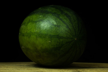 Watermelon big drop on wood, on a black background.