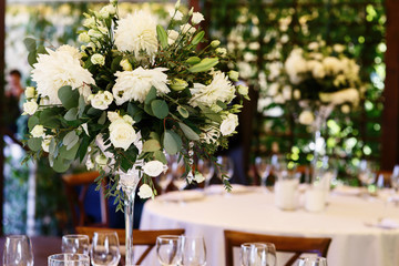 Gorgeous white bouquet stands in the middle of white dinner tabl