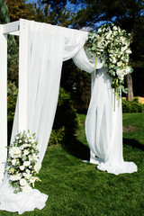 Large white bouquet with greenery stands before wedding altar wi