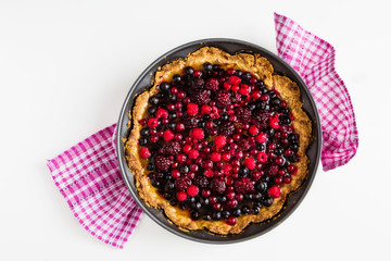 Open round cake with berries, raspberries, blackberries, red and black currant jelly. Shortbread dough, a layer of cheese. White  table, top view.