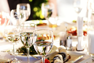 Glasses with wine and water stand on festive served dinner table