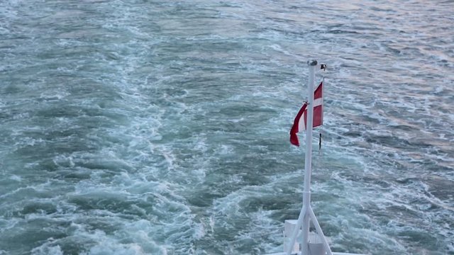 Danish flag closeup waving in the wind on the stern of the ship. The ferry sails from Denmark to Sweden and back