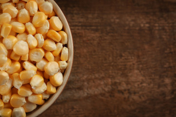 Bowl with corn seeds on wooden rustic table, closeup