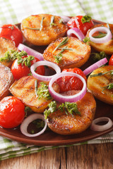 Grilled new potatoes and tomatoes with rosemary and onion macro on a plate. vertical