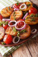 Grilled new potatoes and tomatoes with rosemary and parsley close-up on a plate. vertical