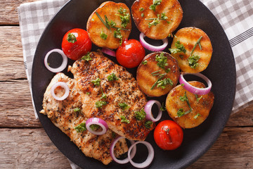 Country Food: Chicken meat grilled with new potatoes and tomatoes close-up. Horizontal top view