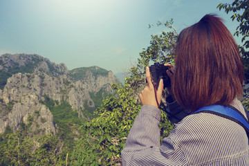 young girl with backpack taking photo of amazing landscape  