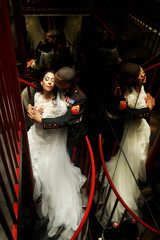 Fototapeta premium Look from above at man hugging bride tender on spiral stairs wit