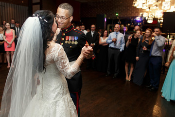 Happy groom in military uniform dances with beautiful bride in t