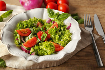 Tasty vegetable salad with cutlery on kitchen table