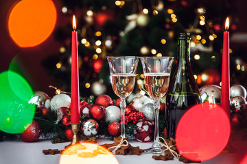 Christmas still life - Two Stemware of champagne with Xmas decorations and Christmas tree on blurred red background